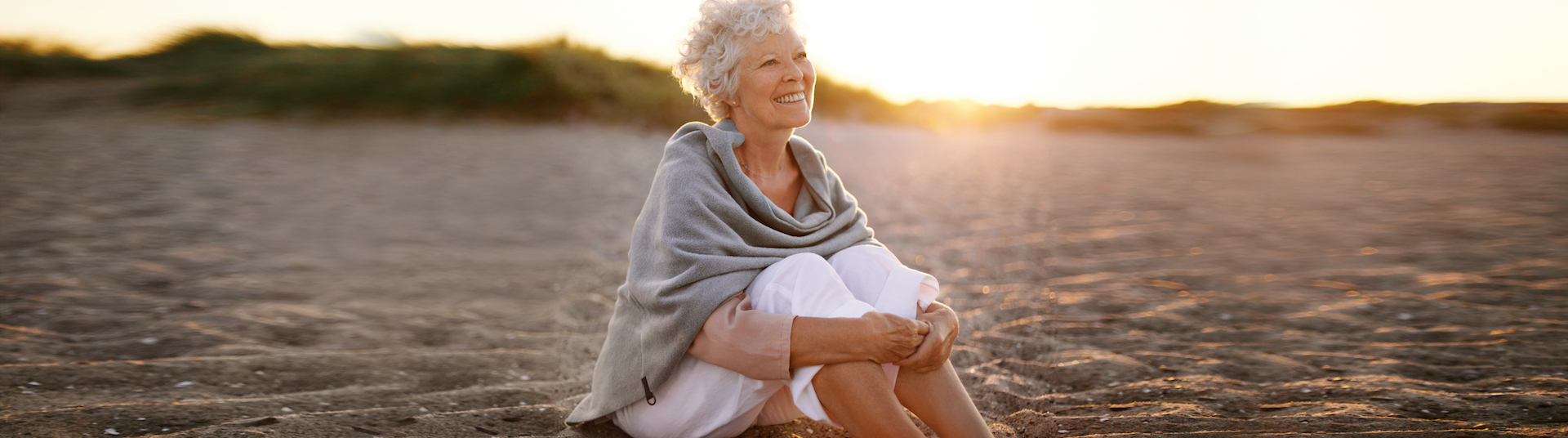 Cheerful old woman sitting on the beach